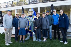 George Albro's family and tournament participants pose with Worcester State mascot Chandler H. Lancer on the lawn outside the clubhouse