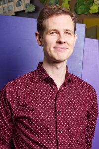 A man stands and smiles.