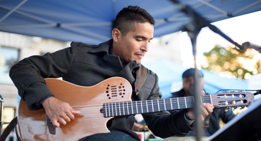 Carlos Odria plays guitar on an outdoor stage