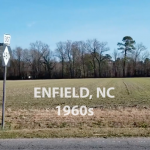 Field along side of road with road signs for North 301 and East 481 and headline Enfield, NC 1960s
