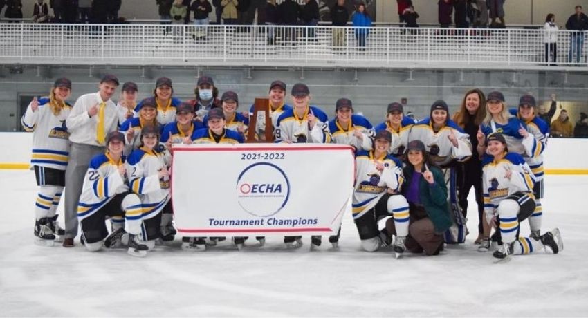 womens ice hockey team on the ice holding ECHA Tournament Champions banner