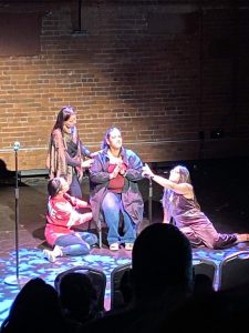 Four women on stage in a theater