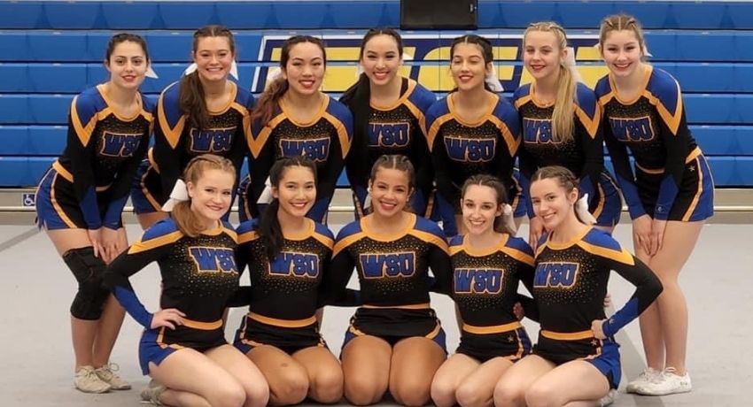 12 members of the WSU cheerleading team posing in their uniforms