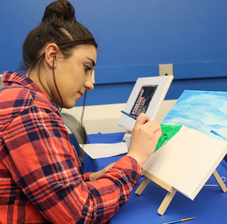 A student focusing on her painting