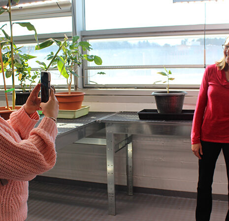 A student takes a photo of professors Jen. Hood-DeGrenier and Aleel Grennan