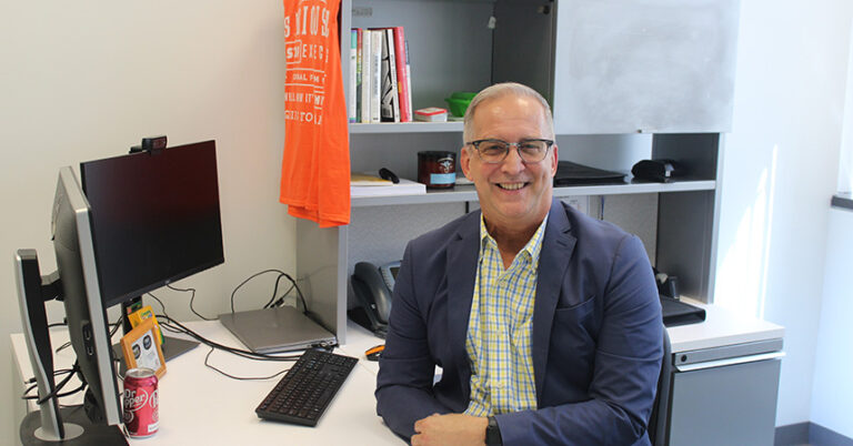 Dannie Lacls seated at his desk smiling