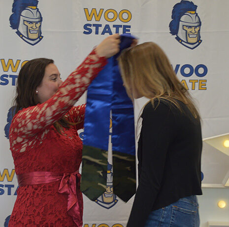 Stephanie Teixeira places an honorary shawl on a graduating student