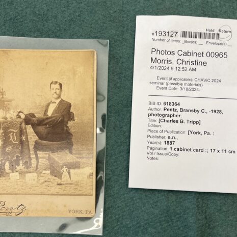A photo of Charles B. Tripp, a man with no arms, sitting at a table and using his feet to handle a teacup