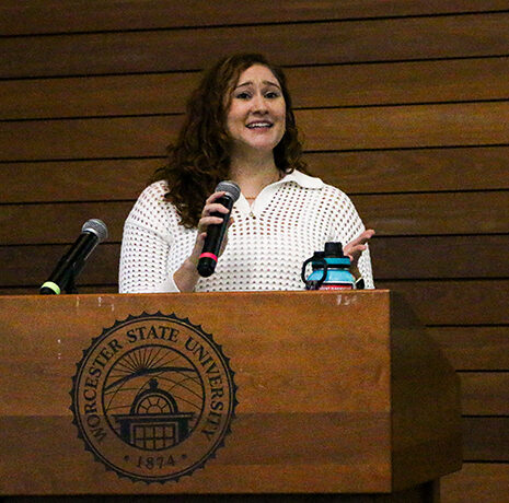 A woman stands at a podium labeled 