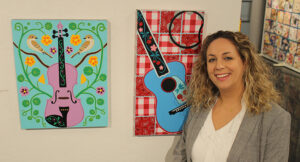 A woman smiling next to a painting.