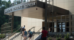 Students walk toward the entrance of a building labeled "Learning Resource Center" on a sunny day.