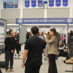 Students present research posters in a gymnasium at Worcester State University during an academic event.