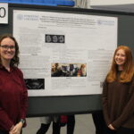 Two young women stand in front of a research poster titled “Effective Motor Speech Intervention for Severe Non-Fluent Apraxia of Speech” at a presentation event, with poster board number 120.