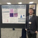 A man in a suit stands next to a scientific poster titled "Breast Cancer Analysis via Machine Learning of Medical Images" at an academic conference.