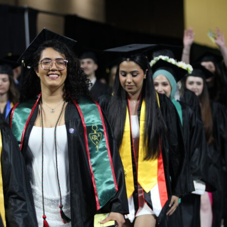 A group of students in graduation caps and gowns walk in a line during a commencement ceremony.