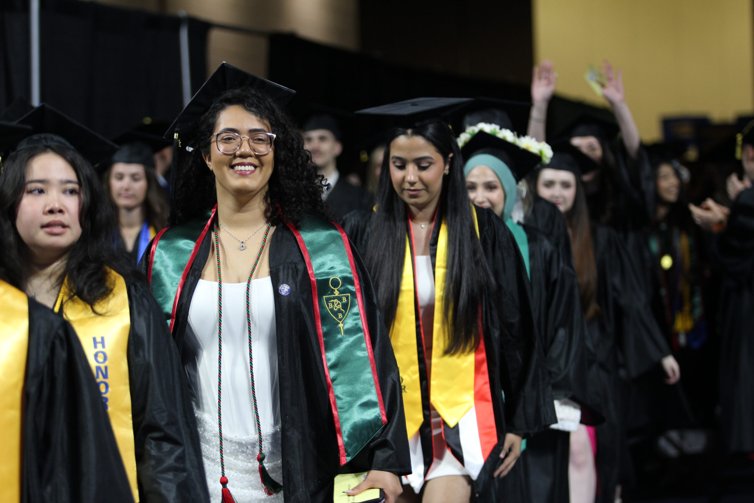 A group of students in graduation caps and gowns walk in a line during a commencement ceremony.