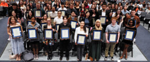 A group of students holding framed awards.