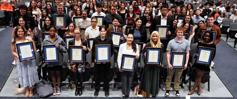 A group of students holding framed awards.